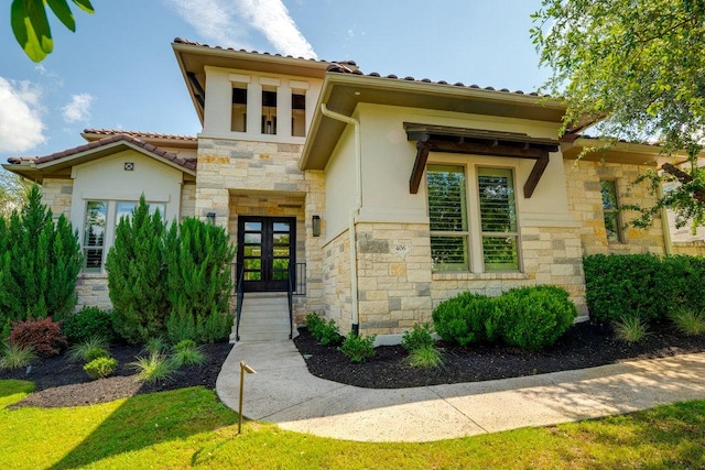 view of front of home featuring french doors, stone siding, and stucco siding
