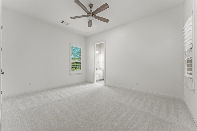 spare room featuring ceiling fan, light carpet, and baseboards