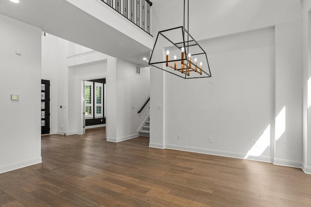 unfurnished living room with stairs, wood finished floors, baseboards, a high ceiling, and recessed lighting