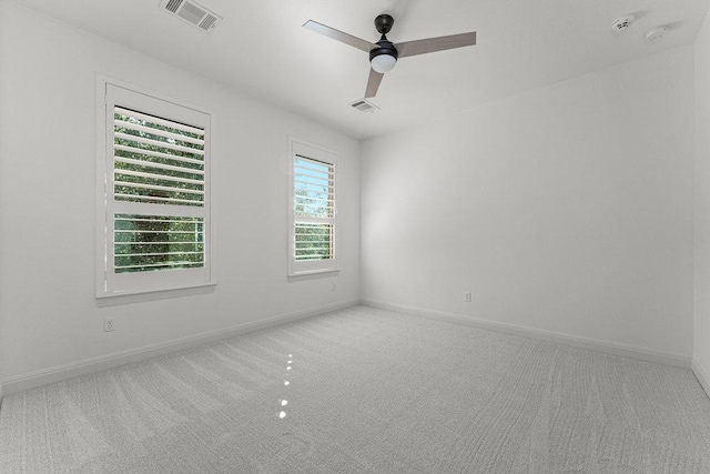 carpeted spare room featuring ceiling fan, baseboards, and a smoke detector