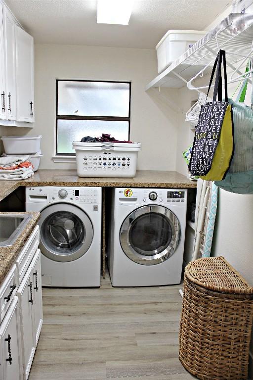 3616 Arrowhead Cir, Round Rock, TX 78681 - laundry area featuring washing machine and dryer, light wood-style flooring, and cabinet space