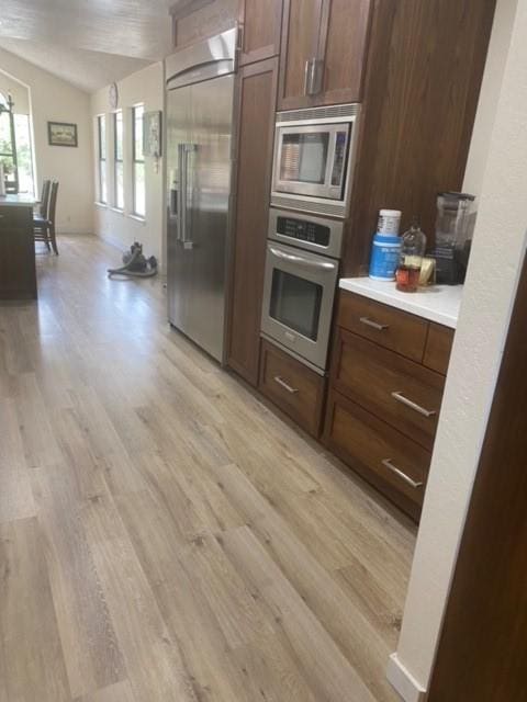 3616 Arrowhead Cir, Round Rock, TX 78681 - kitchen with built in appliances, light wood-style flooring, light countertops, and lofted ceiling