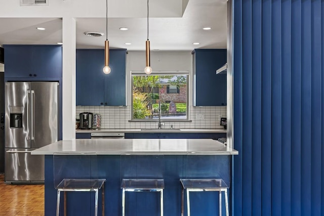 202 Tanglewood Dr, Fredericksburg, TX 78624 - kitchen featuring stainless steel fridge with ice dispenser, a sink, blue cabinets, a breakfast bar area, and decorative backsplash