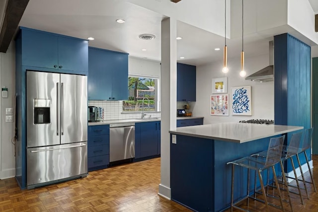 202 Tanglewood Dr, Fredericksburg, TX 78624 - kitchen with appliances with stainless steel finishes, blue cabinets, a sink, tasteful backsplash, and wall chimney exhaust hood