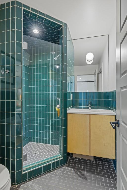 202 Tanglewood Dr, Fredericksburg, TX 78624 - full bath featuring a shower stall, tile patterned flooring, vanity, toilet, and tile walls