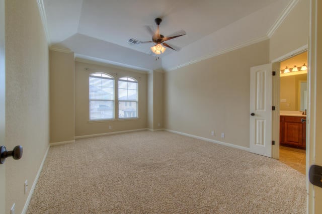 spare room with a ceiling fan, crown molding, a raised ceiling, light carpet, and baseboards