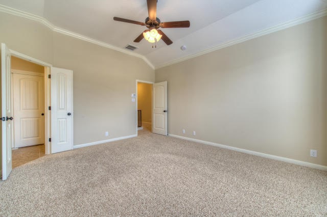 unfurnished bedroom with crown molding, light carpet, baseboards, lofted ceiling, and ceiling fan