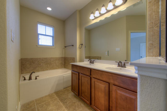 bathroom featuring a bath, tile patterned floors, and double vanity