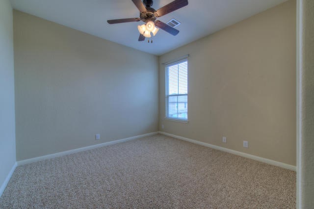 empty room with carpet flooring, baseboards, and a ceiling fan