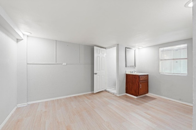 201 N Bowie Ave, Cameron, TX 76520 - below grade area with light wood-type flooring, baseboards, and a sink
