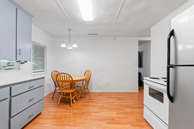 201 N Bowie Ave, Cameron, TX 76520 - kitchen featuring freestanding refrigerator, white range with electric stovetop, gray cabinets, light wood finished floors, and light countertops