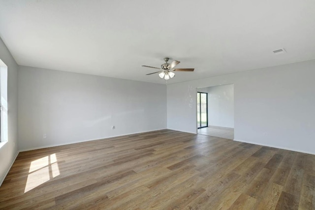 empty room with light wood-type flooring, a ceiling fan, and baseboards