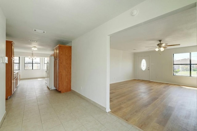 spare room with a chandelier, plenty of natural light, a ceiling fan, and baseboards