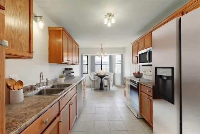 kitchen featuring appliances with stainless steel finishes, a sink, a chandelier, light tile patterned floors, and pendant lighting