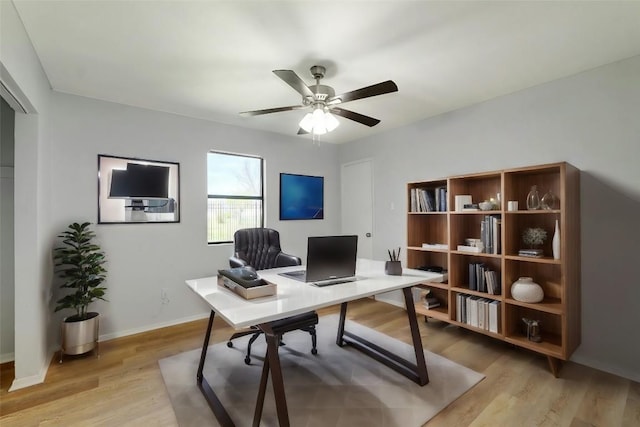 office featuring light wood-style floors, a ceiling fan, and baseboards