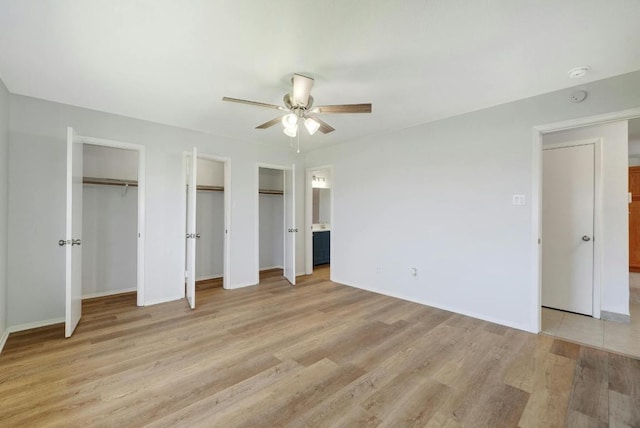 unfurnished bedroom with multiple closets, light wood-type flooring, baseboards, and a ceiling fan