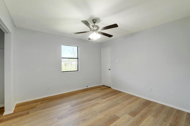 spare room with light wood-style flooring, ceiling fan, and baseboards