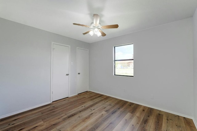 unfurnished room featuring wood finished floors, a ceiling fan, and baseboards