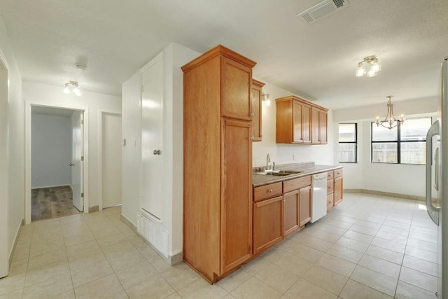 kitchen featuring a sink, white dishwasher, a chandelier, light tile patterned floors, and baseboards
