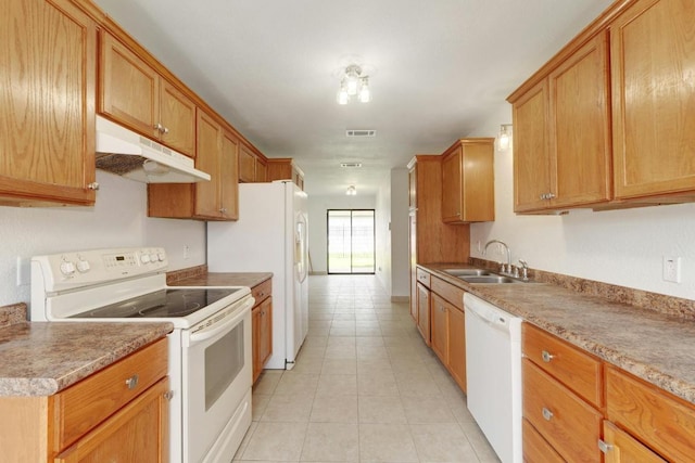 kitchen with white appliances, a sink, under cabinet range hood, light tile patterned flooring, and brown cabinetry