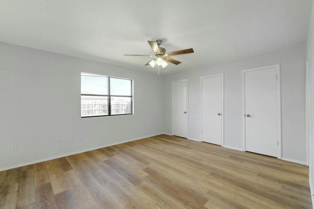 unfurnished bedroom featuring multiple closets, light wood-type flooring, baseboards, and a ceiling fan