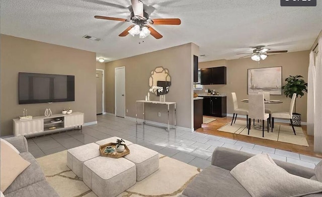 1919 Castle Gate Cir, San Marcos, TX 78666 - living room featuring a ceiling fan, a textured ceiling, and light tile patterned floors