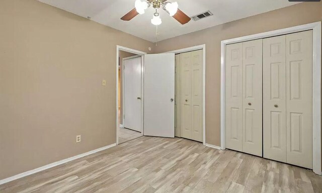 1919 Castle Gate Cir, San Marcos, TX 78666 - unfurnished bedroom with multiple closets, light wood-style flooring, and a ceiling fan