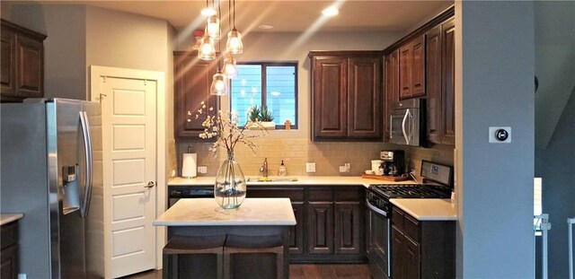 2020 Tripshaw Ln Unit 65C, Austin, TX 78741 - kitchen featuring stainless steel appliances, light countertops, tasteful backsplash, dark brown cabinetry, and a center island