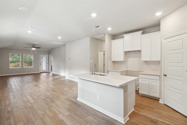 825 Sun Grove Trl, Georgetown, TX 78628 - kitchen featuring a sink, light wood-type flooring, backsplash, a center island with sink, and white cabinetry