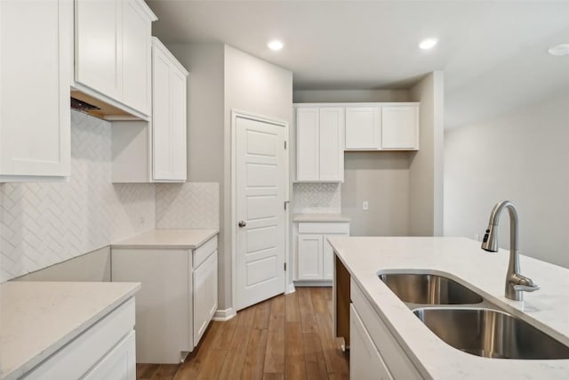 825 Sun Grove Trl, Georgetown, TX 78628 - kitchen featuring a sink, wood finished floors, white cabinetry, recessed lighting, and light stone countertops