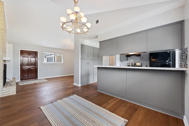 8500 Woodstone Dr, Austin, TX 78757 - kitchen with gray cabinetry, fridge, a chandelier, dark wood-type flooring, and baseboards