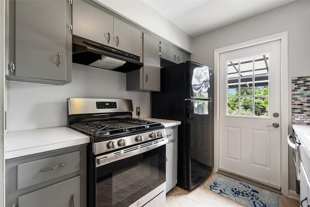 8500 Woodstone Dr, Austin, TX 78757 - kitchen with stainless steel gas range oven, gray cabinetry, under cabinet range hood, and freestanding refrigerator