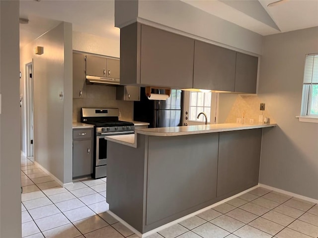 8500 Woodstone Dr, Austin, TX 78757 - kitchen with stainless steel gas range oven, gray cabinetry, under cabinet range hood, a peninsula, and light tile patterned flooring