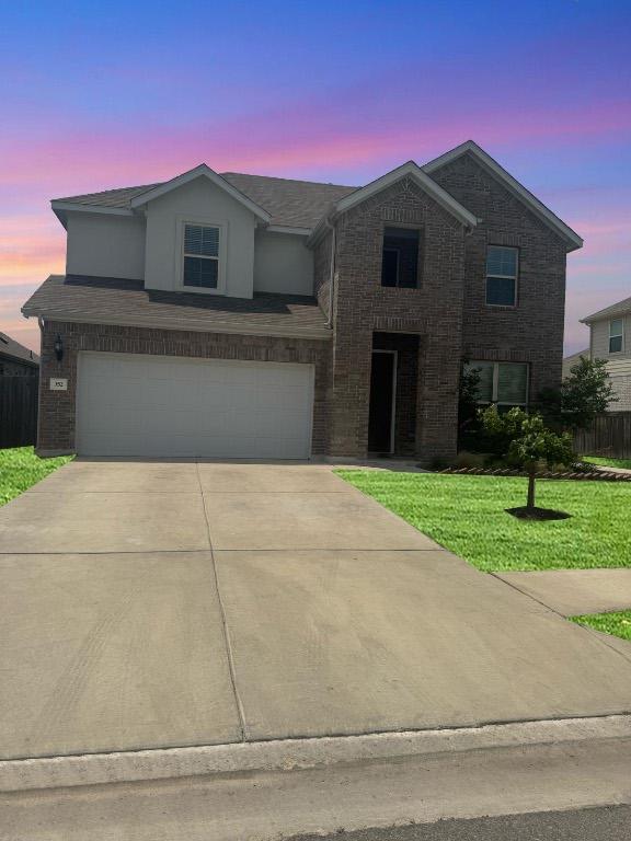 352 Cherrystone Loop, Buda, TX 78610 - traditional-style house featuring an attached garage, driveway, and brick siding