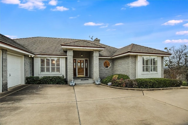1310 Clayton Nolen, Horseshoe Bay, TX 78657 - view of front facade featuring concrete driveway, a chimney, a garage, and brick siding