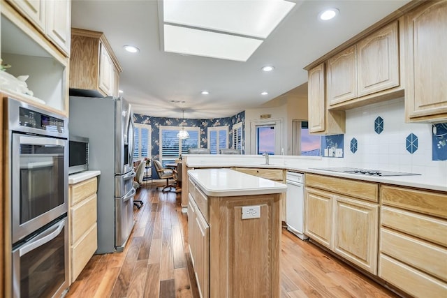 1310 Clayton Nolen, Horseshoe Bay, TX 78657 - kitchen featuring appliances with stainless steel finishes, light brown cabinets, light countertops, a kitchen island, and light wood-type flooring