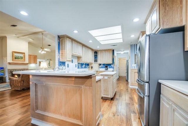 1310 Clayton Nolen, Horseshoe Bay, TX 78657 - kitchen with freestanding refrigerator, light wood-type flooring, a peninsula, light countertops, and glass insert cabinets