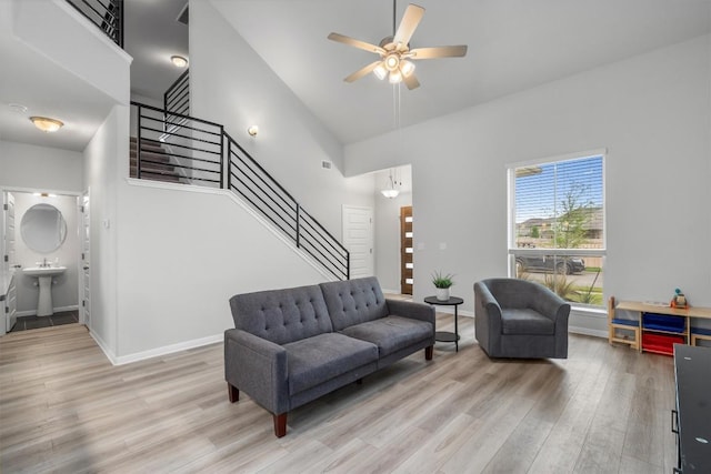 224 Backstays Loop, Kyle, TX 78640 - living room with light wood-style flooring, stairway, a ceiling fan, a towering ceiling, and baseboards