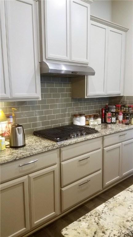 5301 Ponte Tresa Dr, Bee Cave, TX 78738 - kitchen with stainless steel gas stovetop, under cabinet range hood, dark wood-style floors, and tasteful backsplash