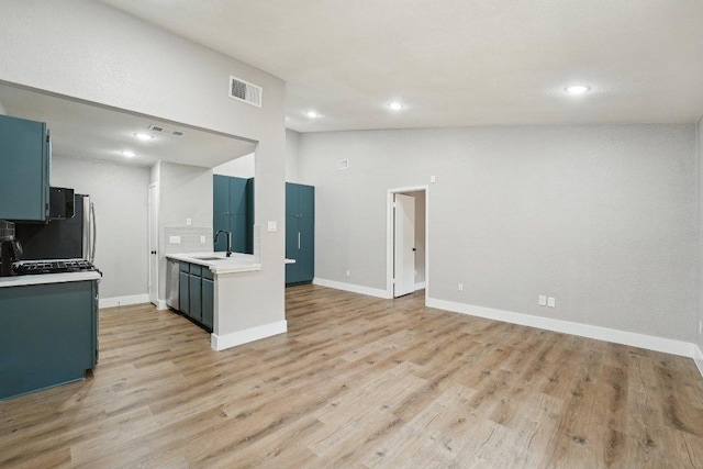 kitchen featuring a sink, light countertops, recessed lighting, light wood finished floors, and baseboards