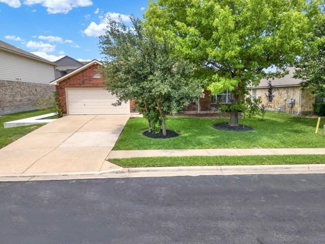 1040 Kensington Castle Trl, Pflugerville, TX 78660 - view of property hidden behind natural elements with concrete driveway, a front lawn, a garage, and brick siding
