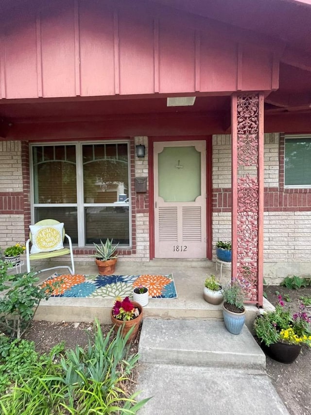 property entrance featuring covered porch and brick siding