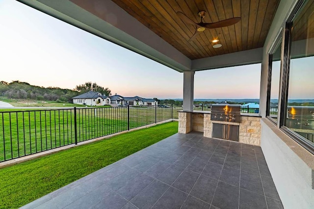 view of patio featuring exterior kitchen, a grill, and a ceiling fan