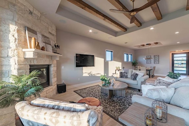 living room with beamed ceiling, a ceiling fan, wood finished floors, baseboards, and healthy amount of natural light