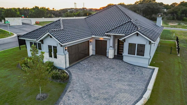 view of front facade featuring an attached garage, stucco siding, a chimney, and decorative driveway