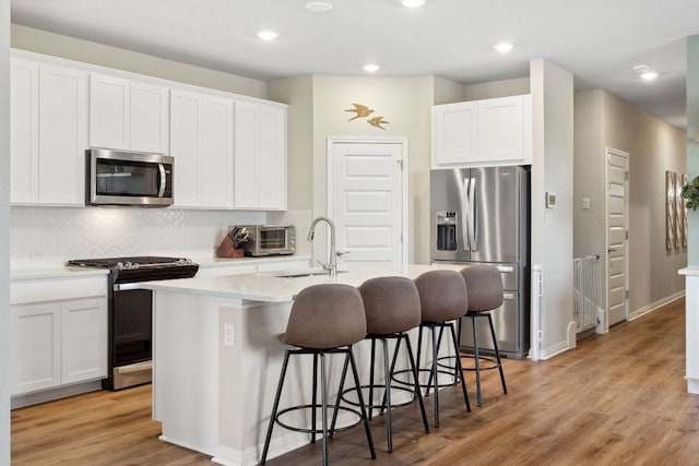 1116 View Dr, Georgetown, TX 78628 - kitchen with appliances with stainless steel finishes, a kitchen island with sink, a breakfast bar, backsplash, and white cabinetry