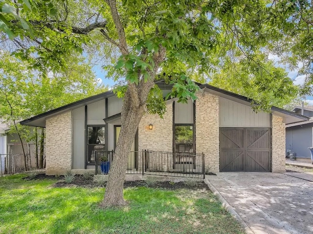 view of front of house with a garage, stone siding, and driveway