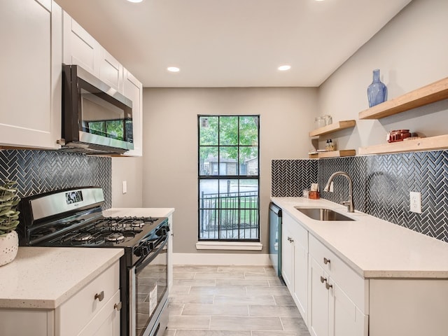 kitchen featuring stainless steel appliances, a sink, open shelves, tasteful backsplash, and white cabinetry