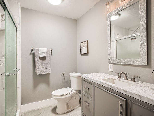 bathroom featuring a stall shower, toilet, vanity, baseboards, and wood finished floors