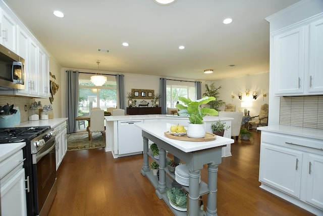 101 Scurry Pass, Georgetown, TX 78633 - kitchen with appliances with stainless steel finishes, a kitchen island, light countertops, white cabinetry, and dark wood finished floors